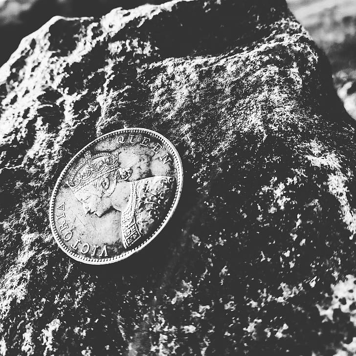 Grayscale Photo of Victoria Queen Coin on Top of Rock