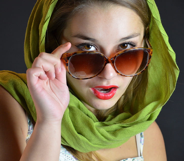 woman wearing green hijab touching oversize sunglasses