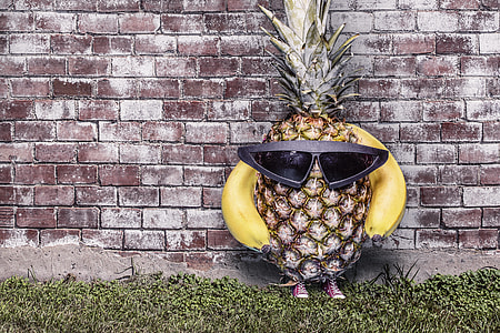 pineapple wearing sunglasses standing beside wall