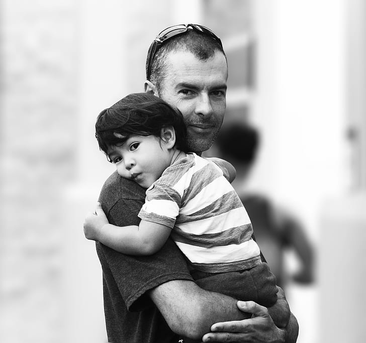 grayscale photography of man carrying baby