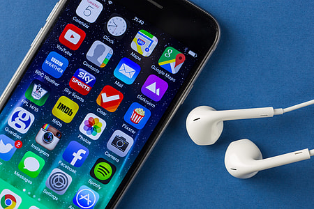 Close-up shot of the iPhone 6 mobile smartphone and earphones on a plain blue background