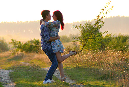 man and woman hugging near grass field