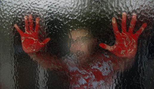 person holding glass with bloody hands