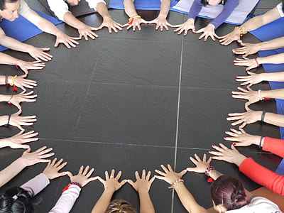 group of people putting hands on black surface