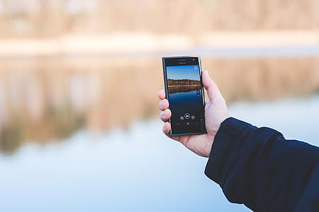 Man taking photo of a lake with mobile phone