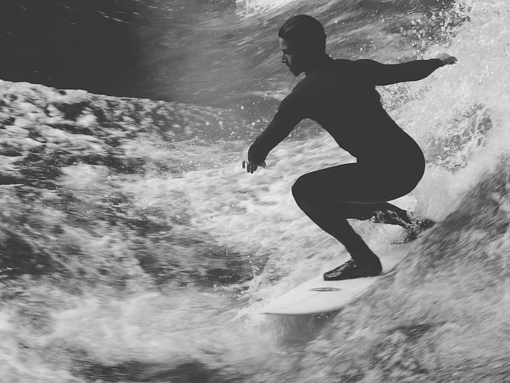 grayscale photo of man riding surfing board