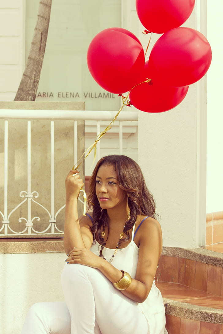 woman wearing white camisole top holding red balloon