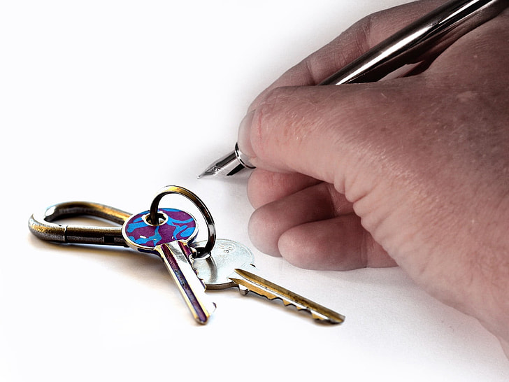 person's holding stainless steel ballpoint pen beside keys