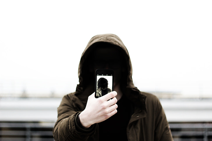 person holding phone wearing brown hoodie