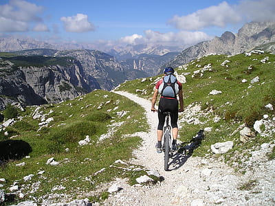man riding mountain bike on peak near gray mountains at daytime