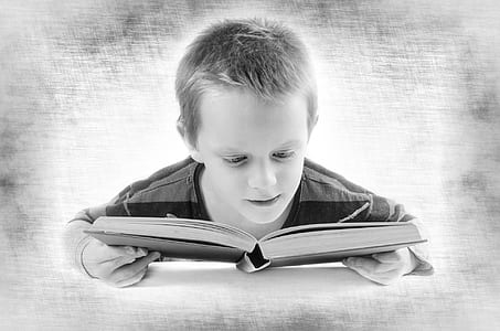 boy reading book grayscale photo