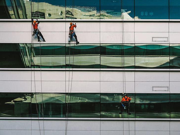 three person climbing on building at daytime