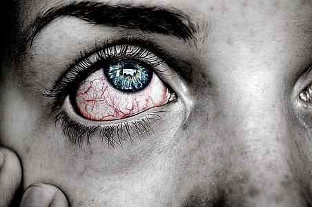 selective color photography of person with bloodshot eyes and blue iris