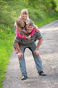 man carrying two girls beside road
