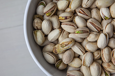 Close up shot of a bowl of pistachio nuts sitting on a wooden table, image captured with a Canon 5D