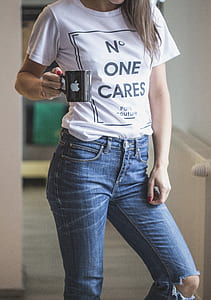 woman wearing white shirt and blue jeans holding black ceramic coffee mug with Apple logo