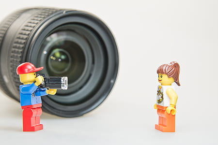 two male and female LEGO minifigures in front black camera lens