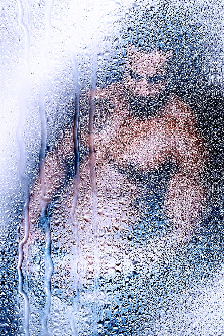 topless man viewed on glass with water droplets