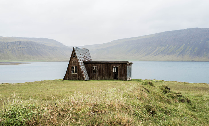 brown and gray wooden house on green grass field during day time