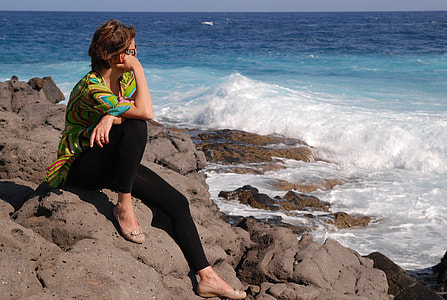 woman in black leggings sitting on rocks near the shore