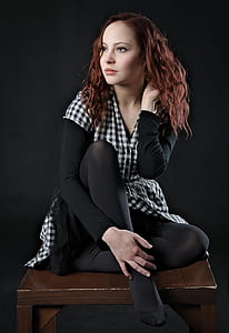 woman wearing black and white checkered dress sitting on brown wooden table