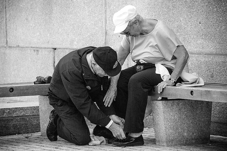 man kneeling on floor in front of woman sitting on concrete bench