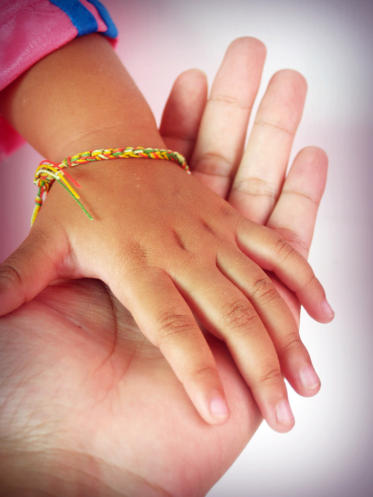 person's hand holding child's hand