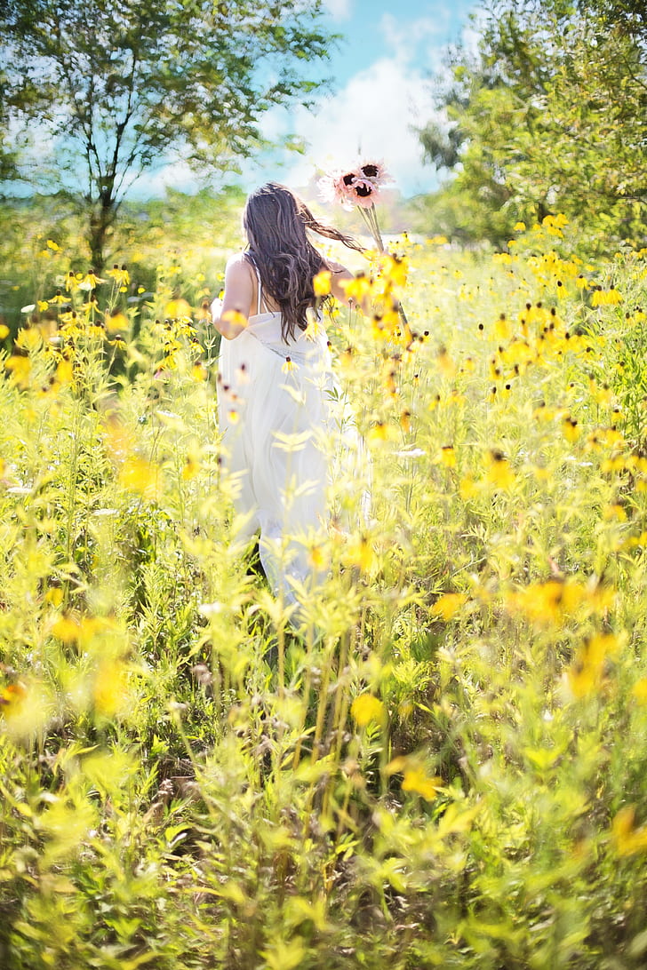 woman wearing white dress on bed of yellow flowers