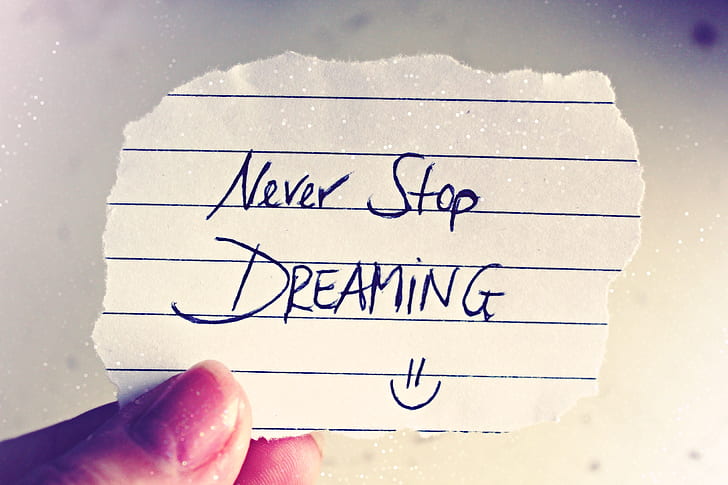 person holding crop paper with Never Stop Dreaming note