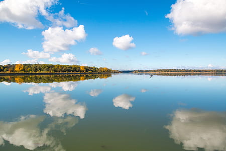 body of water with clouds and sky reflection