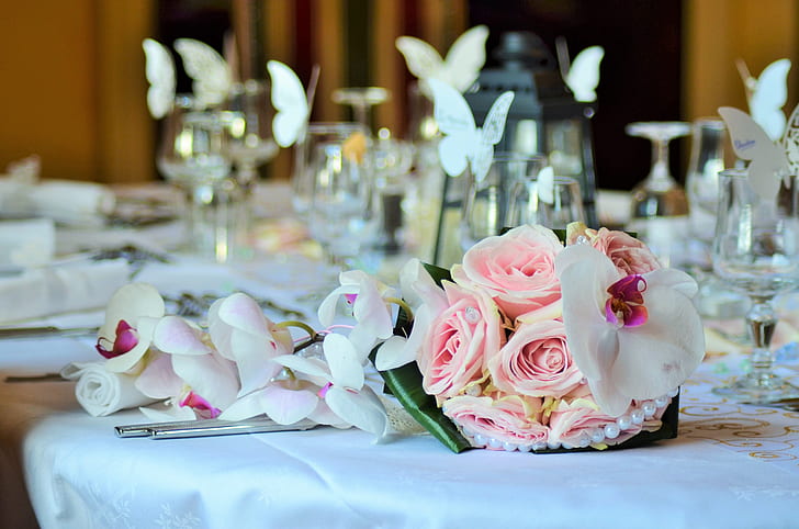 pink rose bouquet beside white orchids on table