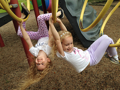 two girls hanging holding yellow bars