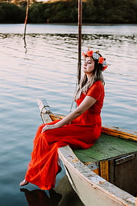 woman in red dress sitting on white wooden boat during daytime