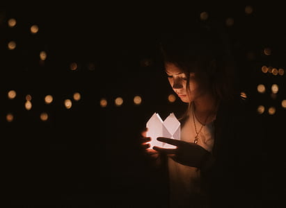 photo of woman holding lit paper during nighttime