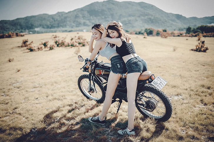 two women riding motorcycle near mountain during daytime