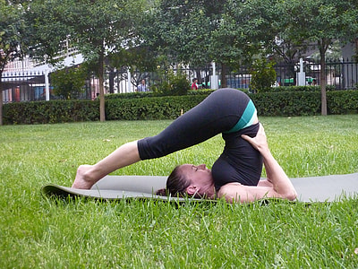 woman wearing black top and leggings bending on gray yoga mat