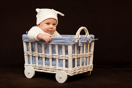 baby wearing white cap riding bassinet