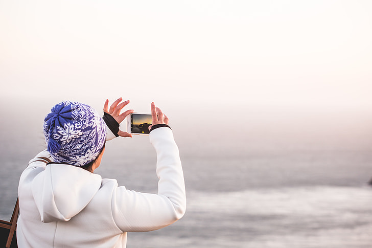Woman in Winter Hat Taking a Picture of Endless Ocean