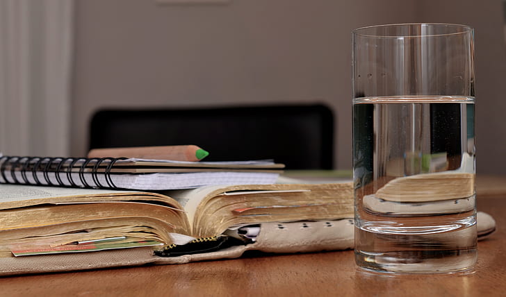 water in clear drinking glass and title book on table