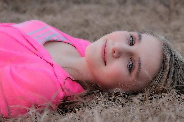 woman wearing pink shirt and lying on brown grassy land
