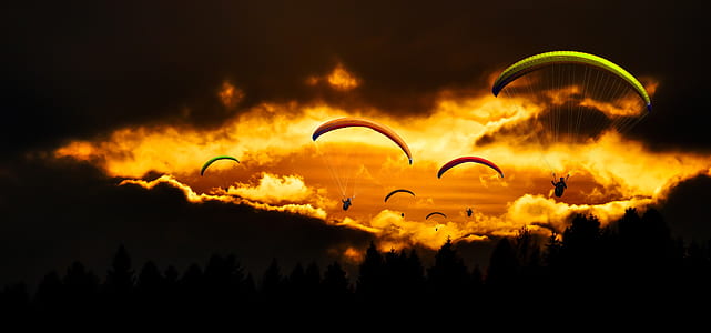 silhouette of parachutes near clouds