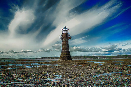 time lapse photography of brown lighthouse underneath blue cloudy skies