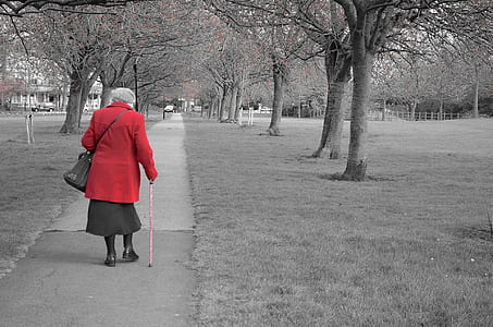 woman in red long-sleeved top walking on gray concrete road