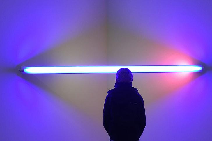 A man stands by abstract lights