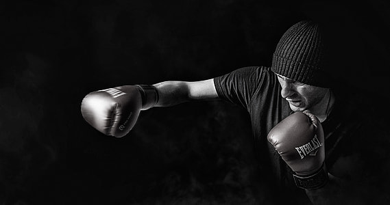 grayscale photo of man wearing beanie and Everlast boxing gloves