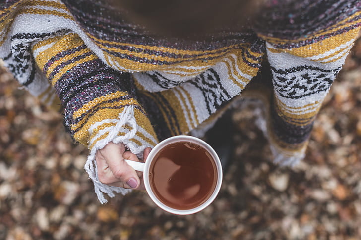 person in sweater holding a filled mug