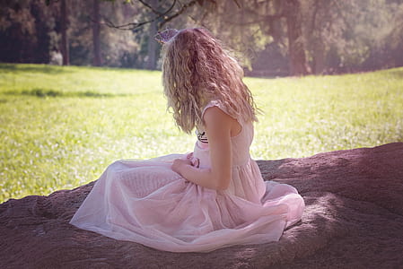 woman wearing white sleeveless dress sitting under tree