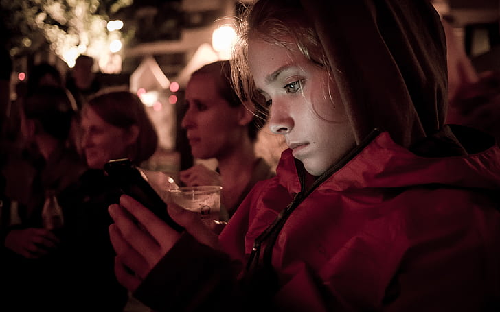 woman in red jacket holding smartphone