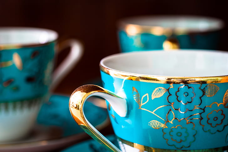 selective focus photography of gold and blue floral mug and saucer
