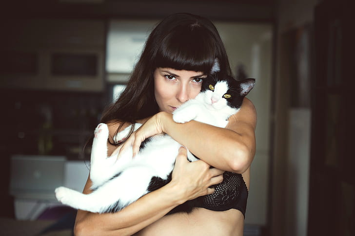 woman hugging black and white Tabby cat